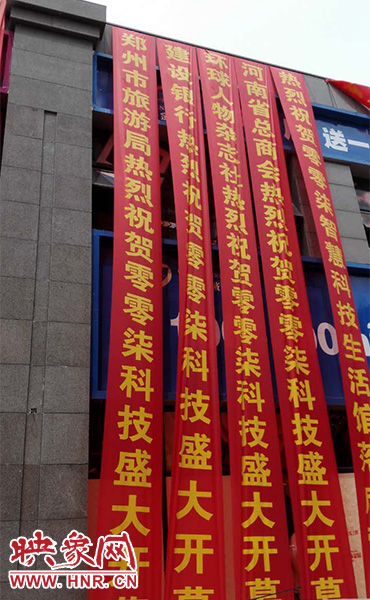路邊一棟樓上懸掛著二三十條紅色條幅，全部是祝賀一家公司開業(yè)的。