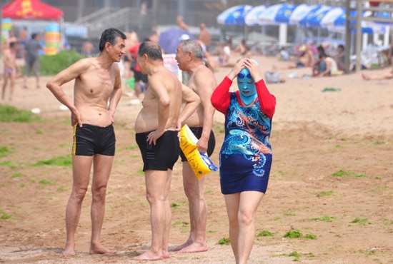 2013年7月3日，山東青島青島高溫來襲，“青島大媽”不懼滸苔，戴著“強(qiáng)盜面具”出現(xiàn)在海水浴場(chǎng)消暑降