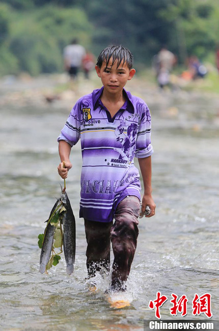 圖為7月9日，一名男孩在鬧魚節(jié)活動中抓到了兩條魚。譚凱興 攝