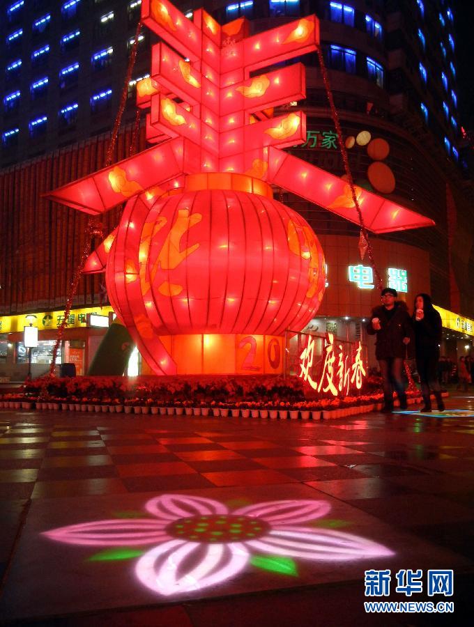 　1月30日晚，市民從蘇州市石路銀河廣場上大型“春”字彩燈景觀旁經(jīng)過。