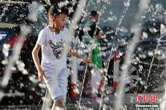 山西太原最高溫36℃,兒童在噴泉周圍戲水消暑。