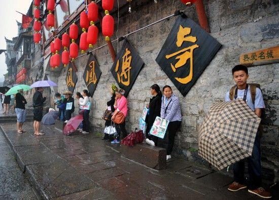 　4月29日上午11時(shí)20分，一些游客和古城當(dāng)?shù)氐木用穸阍谝粋€(gè)酒吧的屋檐下避雨。這些當(dāng)?shù)鼐用褚詾橛慰团恼罩\生，一場(chǎng)降雨讓他們的生意更加清淡。