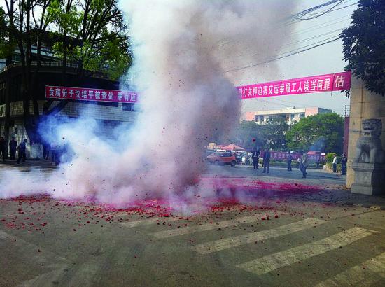 市民在普洱市主干道振興大道的金孔雀交通運(yùn)輸集團(tuán)有限公司門前燃放鞭炮，公司門前掛著“貪腐份子沈培平被查處，罪有應(yīng)得，大快人心?！钡臈l幅