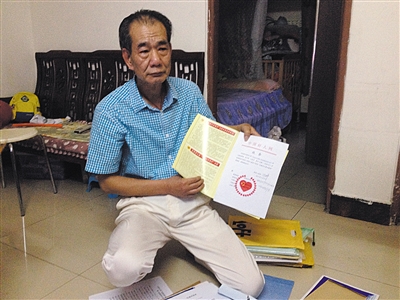 翻出一家網站贈予的“中國好人”證書，區(qū)少坤單膝跪在地上，“你看，我是中國好人啊?！?范春旭 攝
