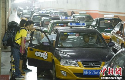 市民在北京西客站出租車候車點(diǎn)準(zhǔn)備乘車。中新社發(fā) 侯宇 攝