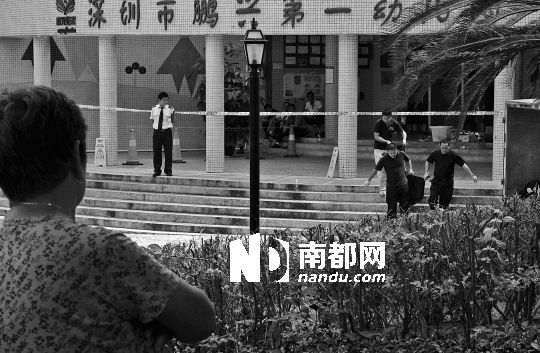 →7月19日，鵬興花園第一幼兒園門前，民警在現(xiàn)場進(jìn)行完勘查取證后，園長和保安的尸體被運(yùn)走。南都記者 徐文閣 攝