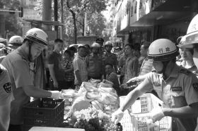 7月11日，瀏陽(yáng)市北正中路，執(zhí)法人員暫扣張海的水果。這是瀏陽(yáng)市城管局拍攝的執(zhí)法現(xiàn)場(chǎng)圖。