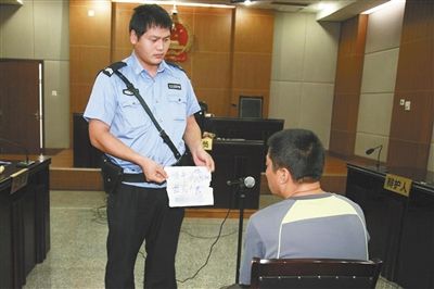 昨日庭審中，法警向趙某出示其扎完車胎后所留辱罵公司的紙條。通訊員 李秀文 攝