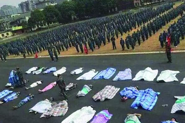 20多名女生躺在瀝青跑道上，身上嚴(yán)嚴(yán)實(shí)實(shí)地裹著棉被，接受太陽(yáng)的照曬。