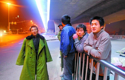 冬夜里，農(nóng)民工在橋下等著干活兒。