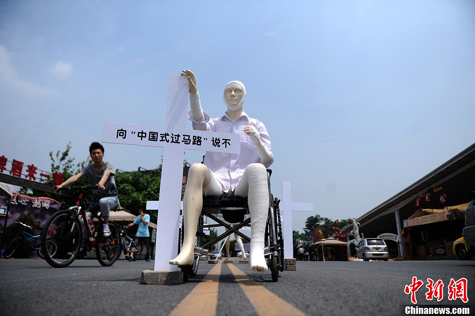 4月16日，重慶市洋人街上擺放著兩個(gè)受了傷的塑料人像“模特”，旁邊十字架上寫(xiě)著向“中國(guó)式過(guò)馬路”說(shuō)不