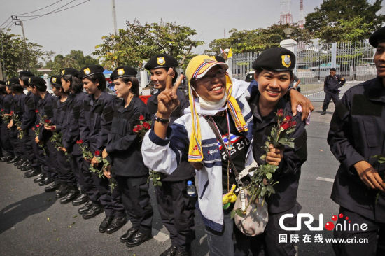 2013年12月03日,曼谷總理府與曼谷警署允許反政府示威民眾進(jìn)入,雙方進(jìn)入暫時“停戰(zhàn)”狀態(tài)迎接泰王生日。曼谷警察總署,女警們手持鮮花送給反政府示威民眾。圖片來源:Manish Swarup/東方IC