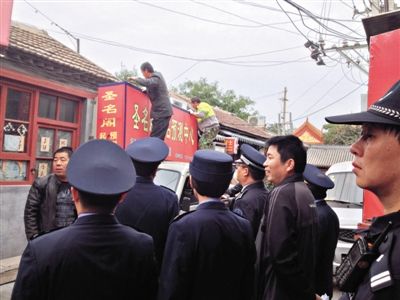 昨日下午,東城區(qū)工商、城管、公安等部門,對雍和宮附近的預(yù)測中心進(jìn)行清理整頓,站在車頂?shù)膬擅と苏鸪患摇邦A(yù)測中心”的招牌。因雍和宮、白云觀等文化景點外聚集大量算命先生,被媒體稱為“算命一條街”。本版攝影/新京報記者 李寧 攝