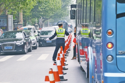 省人民醫(yī)院南門的路中間擺放反光錐，交警示意由西向東車輛從前方繞行。