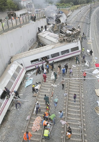 24日，救援人員在西班牙列車脫軌現(xiàn)場。一節(jié)車廂被強大的慣性拋上鐵道邊的高臺。