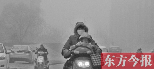 12月8日，鄭州市未來路上，一位市民帶著孩子在霧中騎行