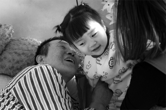 病床前李剛父女倆說著“悄悄話”，幸福的氣氛洋溢在病房中