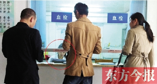 昨日，鄭州市二七區(qū)疾控中心辦證大廳，血檢窗口內(nèi)一名女工作人員，邊接受辦證者咨詢邊看報紙