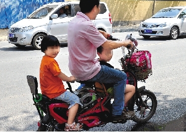 周先生騎著一輛低矮的電動(dòng)車帶著一對(duì)兒女，很不安全。