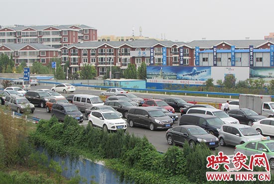 記者看到鄭州機(jī)場(chǎng)收費(fèi)站口車(chē)輛排隊(duì)，與此形成鮮明對(duì)比的是，路的對(duì)面（另一半幅）卻車(chē)輛較少，通行順暢。