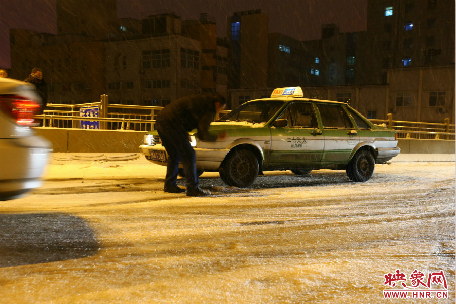 一位出租車司機(jī)在車輪前灑上雪，希望能增加輪胎的摩擦力。