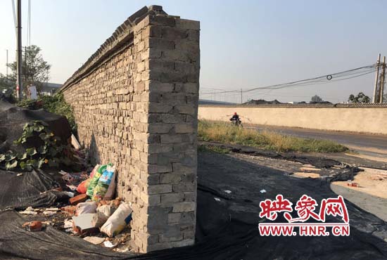 一墻之隔，一邊是道路，一邊是垃圾和荒草，市民質(zhì)疑其為遮羞墻。