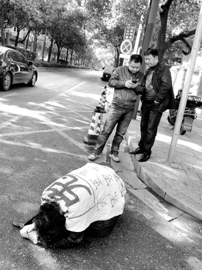 兩名接訪人員與患有癌癥的訪民段新德合影時(shí)，在拍照時(shí)查看手機(jī)。