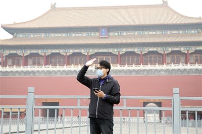 11月1日，北京大部分地區(qū)重度污染，一名游客戴著口罩在午門前揮手跟朋友打招呼。 實習(xí)生 王飛 攝