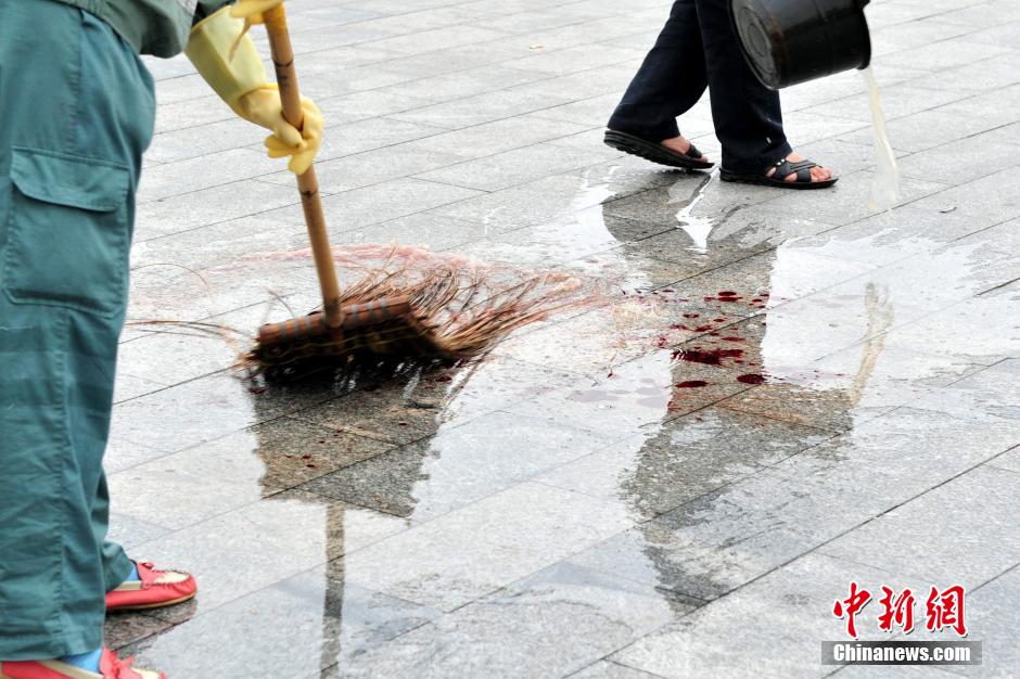 圖為環(huán)衛(wèi)工人在清理案發(fā)地點的血跡。