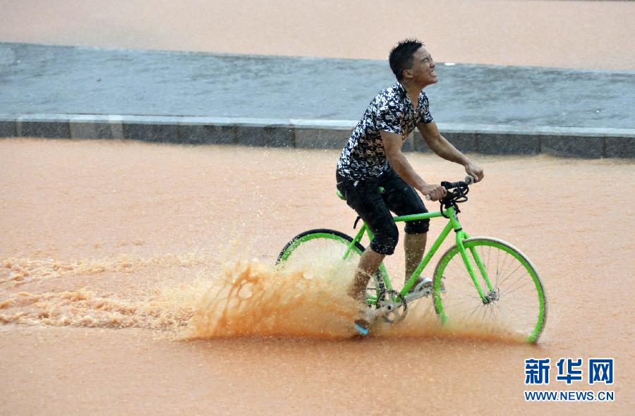 5月11日，一名行人在深圳街頭冒雨騎行。