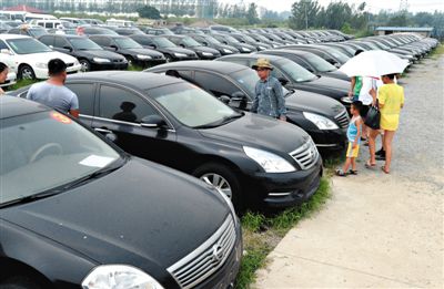 昨日，市民在山東棗莊一家拍賣公司場地上查看待拍賣公車。當(dāng)日，棗莊市103輛公車公開拍賣。新華社記者