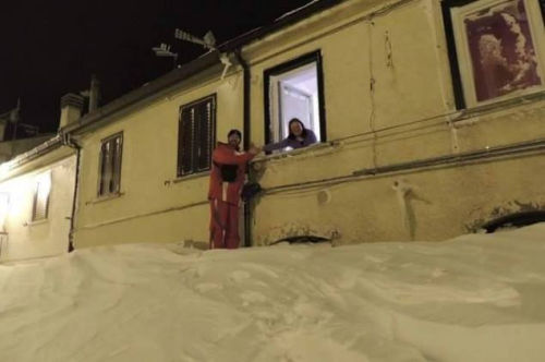 一個居民站在積雪上，可以與一名二樓鄰居在窗口握手。（來源：意大利氣象局）