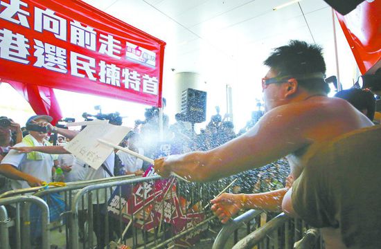 17日，在香港立法會(huì)外，一名反對(duì)政改的男子向支持派人群投擲標(biāo)牌。