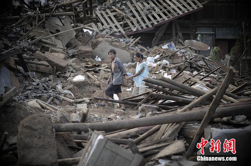 2014年8月5日，云南昭通龍頭山鎮(zhèn)老街，一對(duì)夫妻從居住房屋的廢墟中走過。