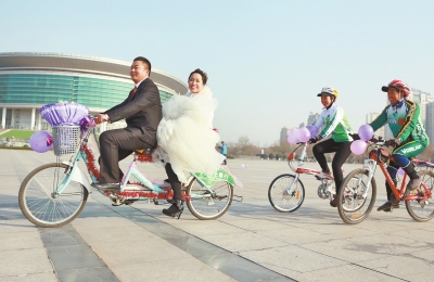 氣球和鮮花裝點(diǎn)的雙人自行車(chē)，新郎郝幸福載著美麗新娘回家。