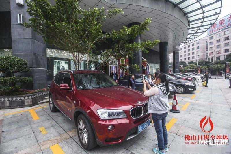 一輛停在停車位上的寶馬轎車，被墜落的樹枝砸中，樹枝徑直插入車內，現(xiàn)場引發(fā)不少市民圍觀拍照。
