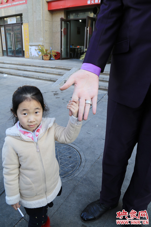 巨人“張歡”牽著一名漂亮的小女孩，兩人的手大小對比非常明顯。