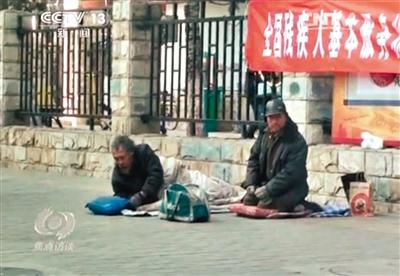 工人體育場(chǎng)北路，兩位乞討者路邊乞討，并輪流扮成“病人”（躺地者）。 央視截圖