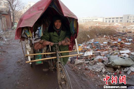 圖為老人走出窩棚，推著三輪車準備出去撿拾廢品。周小云 攝